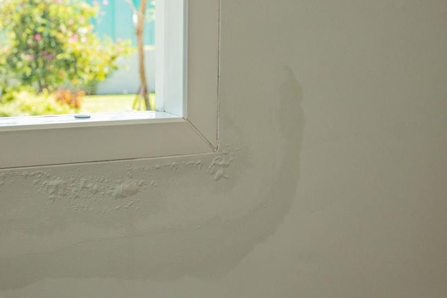 Window with bubbling and peeling wall paint from water damage