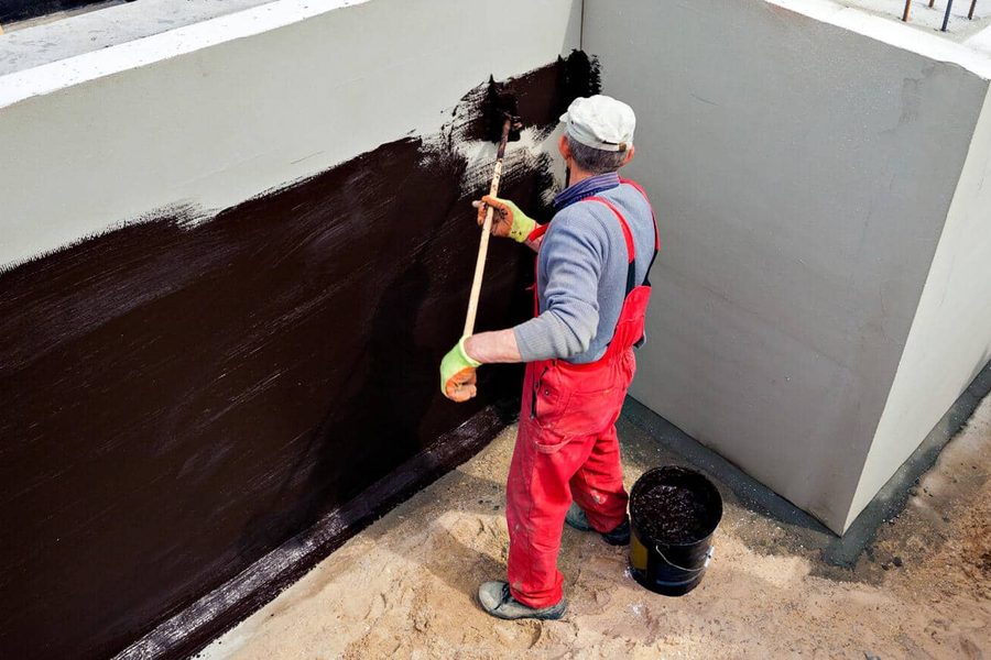 Worker applying waterproofing coating
